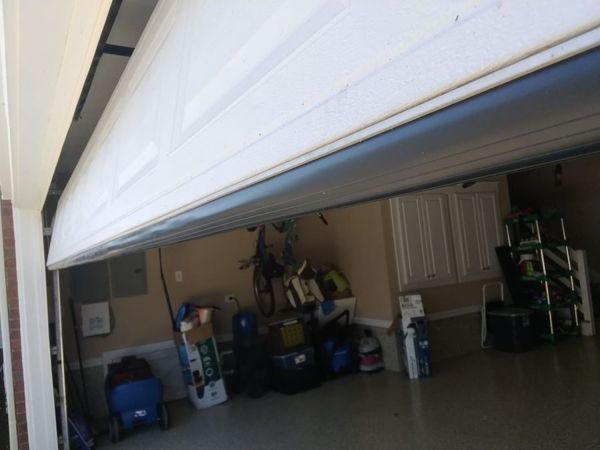 Garage door bottom seal replacement in Virginia Beach: new black T-style bottom rubber installed across the bottom of a raised two-car garage door, October 2026