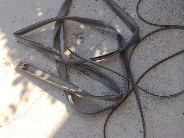 Garage door bottom seal replacement in Virginia Beach: the old flattened gray bottom rubber pulled out of both doors and lying on the driveway, October 2026