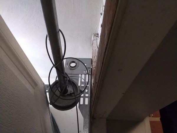 Garage door lift cable that came off its drum and is wrapped loose around the torsion shaft above the door