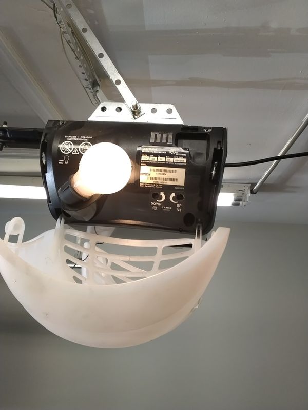 Garage door opener replacement Virginia Beach: 20-year-old opener with its light lens hanging loose before removal