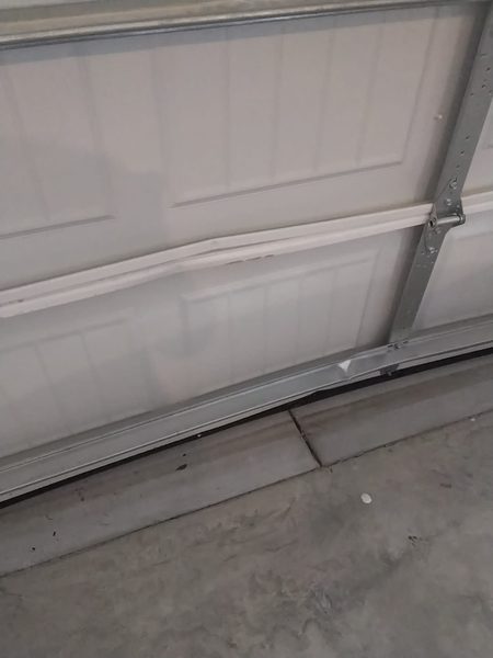 Garage door repair in Portsmouth VA: bottom section creased by a car, ZIP 23701, before the section replacement