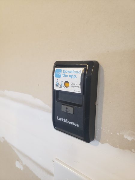 Garage door opener wall console and motor unit in a Hampton Roads garage, used to diagnose a humming opener that will not move the door