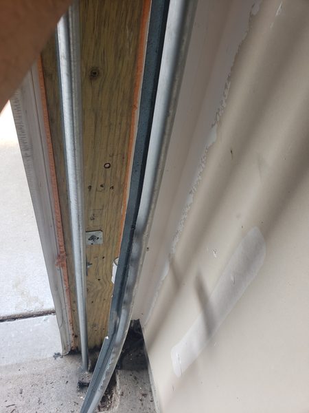 Technician sliding a new sealed-bearing nylon roller into the track during a garage door roller replacement in Virginia Beach